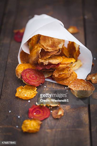 roasted vegetable chips made of parsnips, sweet potatoes, beetroots, carrots and turnips on wooden table - root vegetable stockfoto's en -beelden
