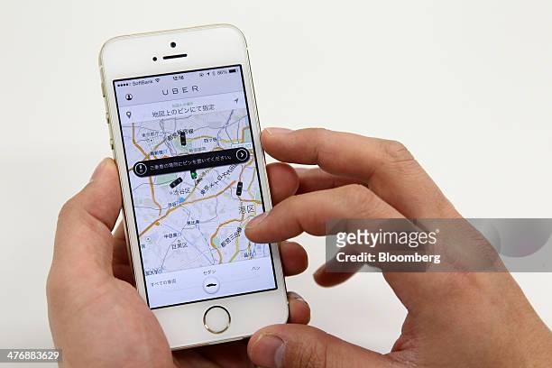 An Uber Japan Co. Employee reserves a car using the Uber application on an Apple Inc. IPhone 5s during a demonstration in the company's office in...