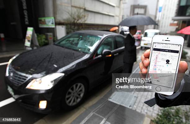 An Uber Japan Co. Employee holds an Apple Inc. IPhone 5s showing a map on the Uber application for a photograph during a demonstration in Tokyo,...