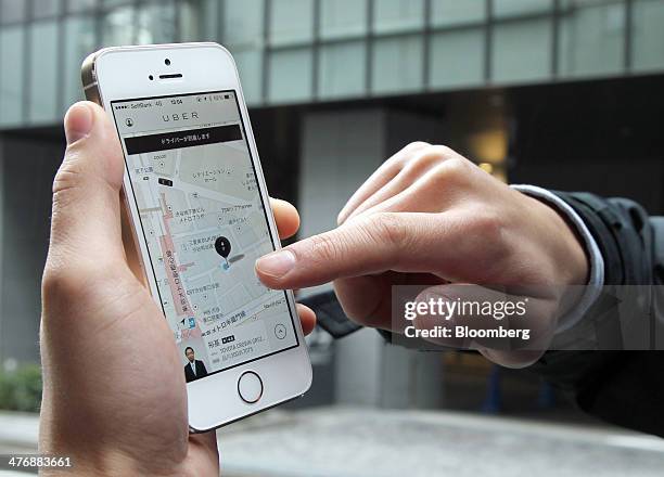 An Uber Japan Co. Employee uses the Uber application on an Apple Inc. IPhone 5s during a demonstration outside the company's office in Tokyo, Japan,...