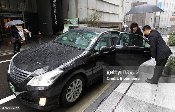 Driver opens the door for a customer during a demonstration outside the Uber Japan Co. Office in Tokyo, Japan, on Wednesday, March 5, 2014. Uber...