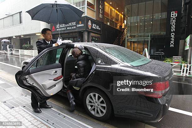 Driver opens the door for a customer during a demonstration outside the Uber Japan Co. Office in Tokyo, Japan, on Wednesday, March 5, 2014. Uber...