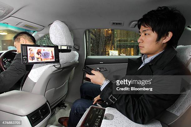 An Uber Japan Co. Employee watches television in a car during a demonstration in Tokyo, Japan, on Wednesday, March 5, 2014. Uber Technologies Inc.,...