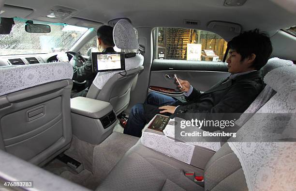 An Uber Japan Co. Employee uses a mobile phone in a car during a demonstration in Tokyo, Japan, on Wednesday, March 5, 2014. Uber Technologies Inc.,...