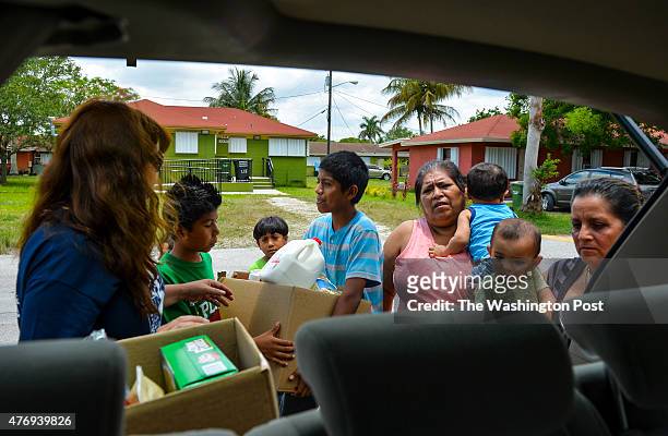 Nora Sandigo-Otero, left, delivers emergency food relief to Leticia Ramires, far right, holding her 5 month-old granddaughter, Cristina Beltran,...