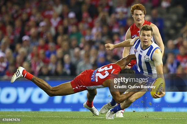 Shaun Higgins of the Kangaroos handballs whilst being tackled by Lewis Jetta of the Swans during the round 11 AFL match between the North Melbourne...