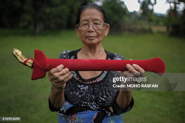 Head shaman from the Kadazan-Dusun tribe Singkaban Kowil holds a dagger called "hulu karis" at her residence in Damat, a village in the district of...