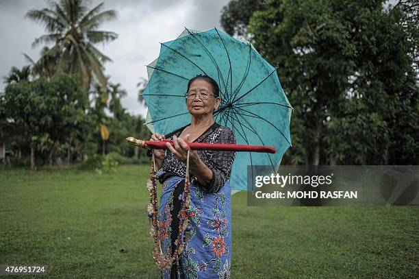 Head shaman from the Kadazan-Dusun tribe Singkaban Kowil holds a dagger called "hulu karis" and an amulet called "kamagi" at her residence in Damat,...