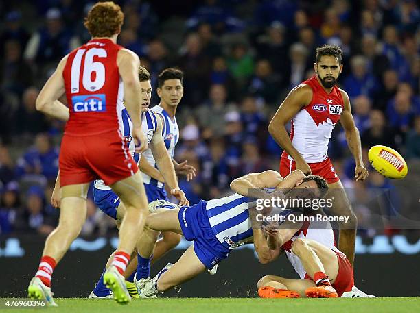 Sam Gibson of the Kangaroos handballs whilst being tackled during the round 11 AFL match between the North Melbourne Kangaroos and the Sydney Swans...