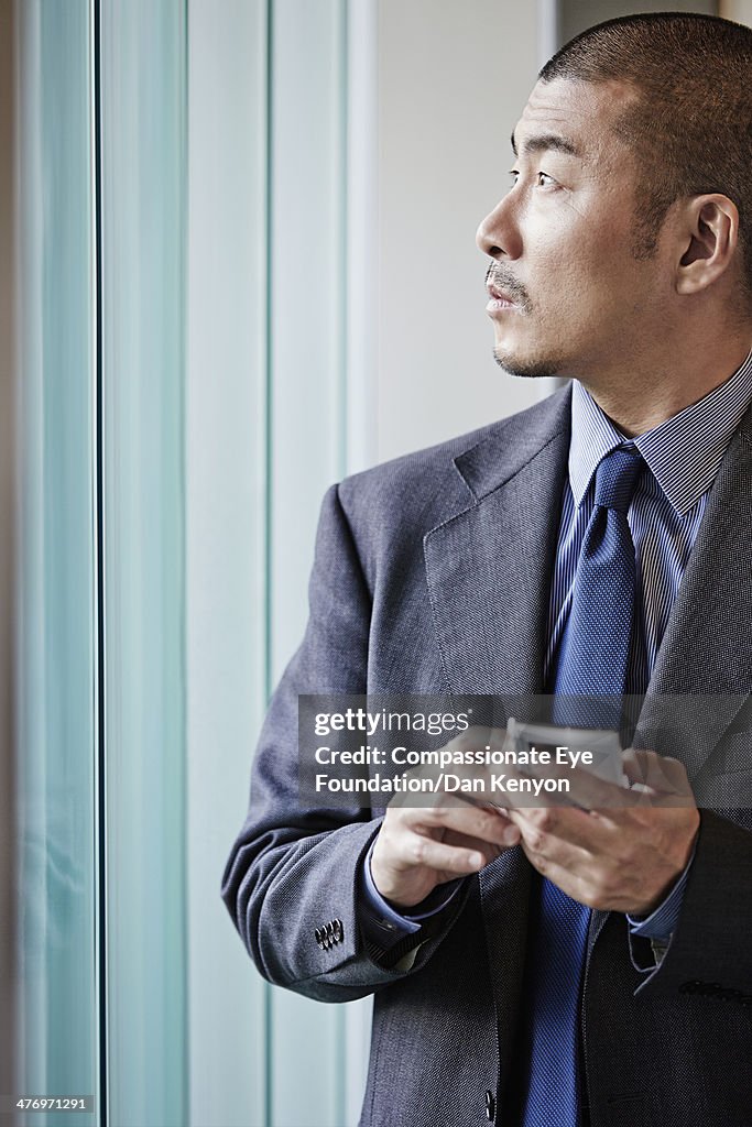 Man with mobile phone, looking out of window
