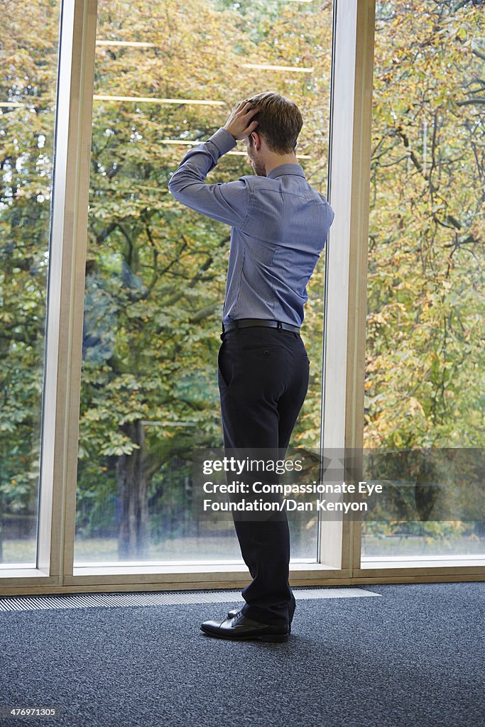 Man on mobile phone, looking out of window