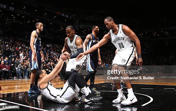 Jason Collins and Tyshawn Taylor of the Brooklyn Nets help teammate Shaun Livingston during a game against the Memphis Grizzlies at the Barclays...