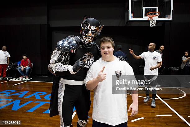 The mascot, BrooklyKnight poses with a fan at a basketball clinic for 65 Special Olympics athletes at Barclays Center on March 3, 2014 in Brooklyn,...