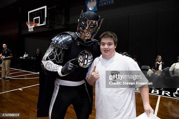 The mascot, BrooklyKnight poses with a fan at a basketball clinic for 65 Special Olympics athletes at Barclays Center on March 3, 2014 in Brooklyn,...