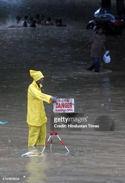 People walks through a flooded street during heavy rain at Parel on June 13, 2015 in Mumbai, India. Heavy rains caused major water logging in many...