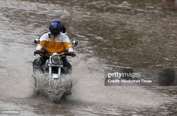 Bikers pass through a flooded street during heavy rain at Parel on June 13, 2015 in Mumbai, India. Heavy rains caused major water logging in many...