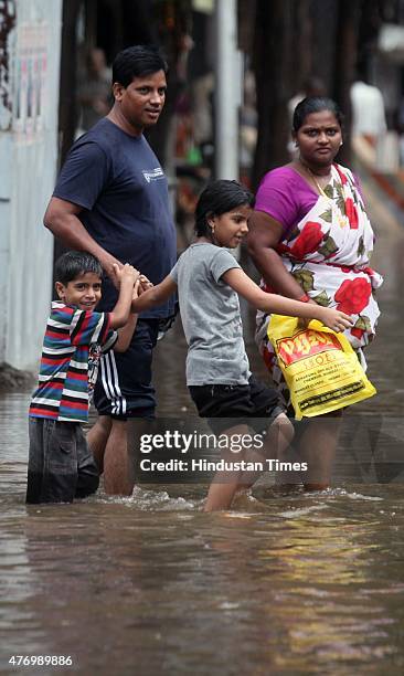 People walks through a flooded street during heavy rain at Hindamata, Dadar on June 13, 2015 in Mumbai, India. Heavy rains caused major water logging...