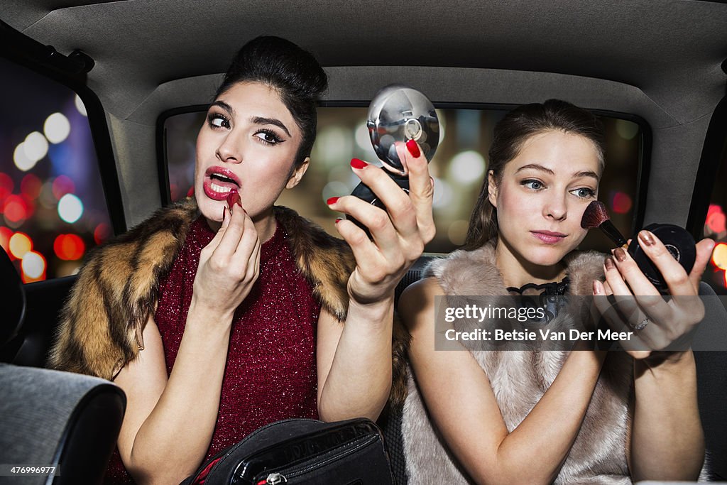 Women touching up make up in car at night time.