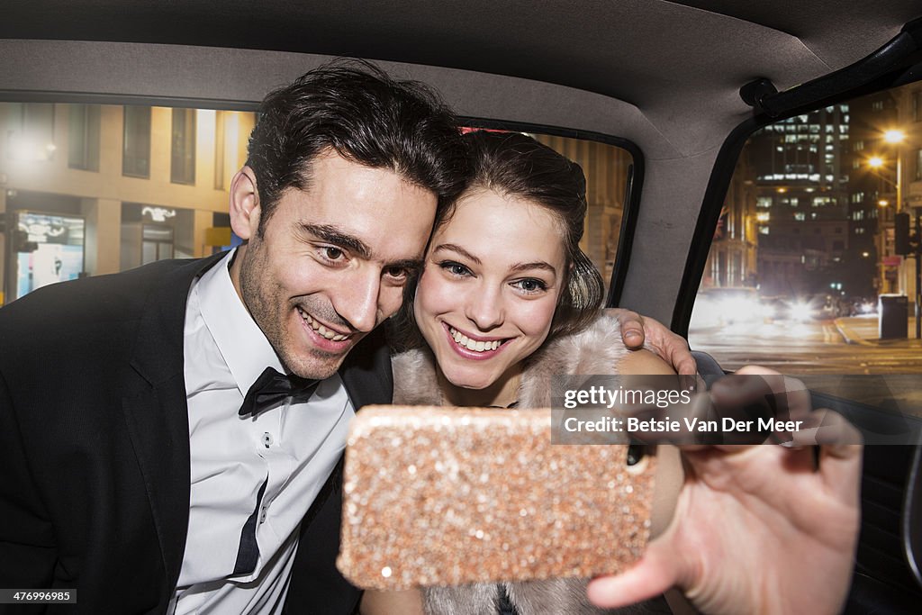 Couple taking self portrait on phone in car.