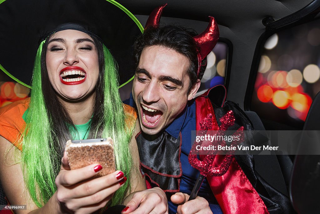 Halloween witch and devil laughing in back of car