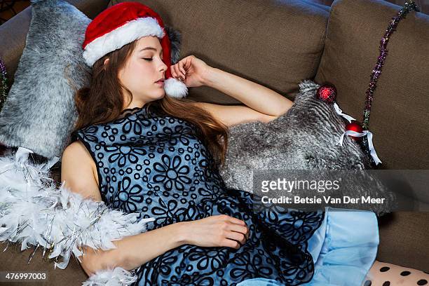 young woman sleeping on sofa wearing christmas hat - room after party fotografías e imágenes de stock