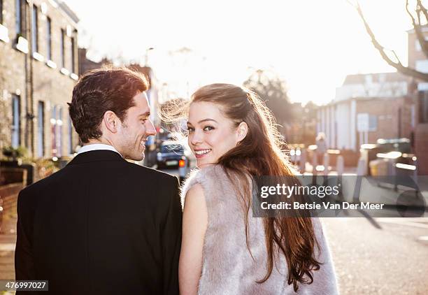 couple walking through the street early sunshine.. - black tie party fancy stock-fotos und bilder