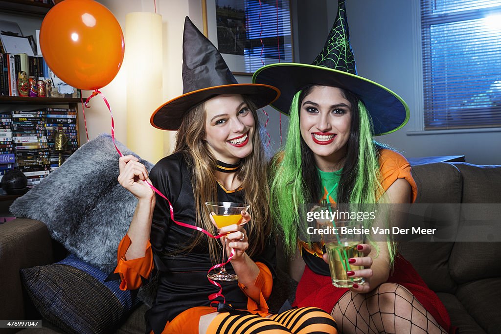 Two women dressed as witches on sofa.