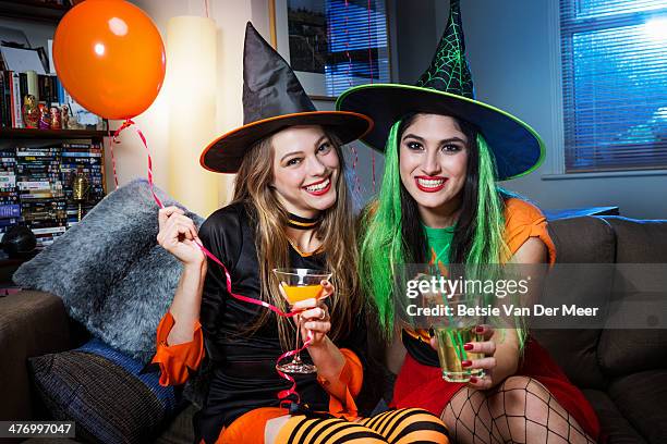 two women dressed as witches on sofa. - cocktail party at home stock pictures, royalty-free photos & images