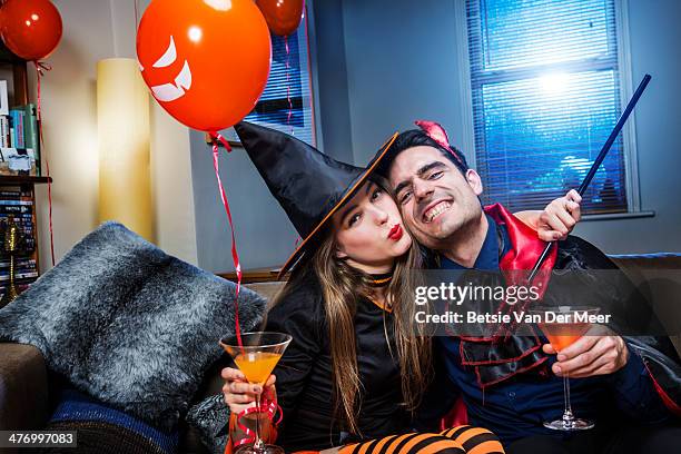 halloween witch and devil on sofa with cocktails. - cocktail party at home stock pictures, royalty-free photos & images