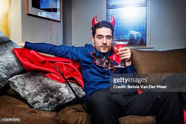 halloween devil relaxing on sofa with cocktail. - disfraz de diablo fotografías e imágenes de stock