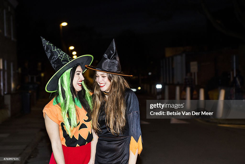 Two witches laughing walking on the street.