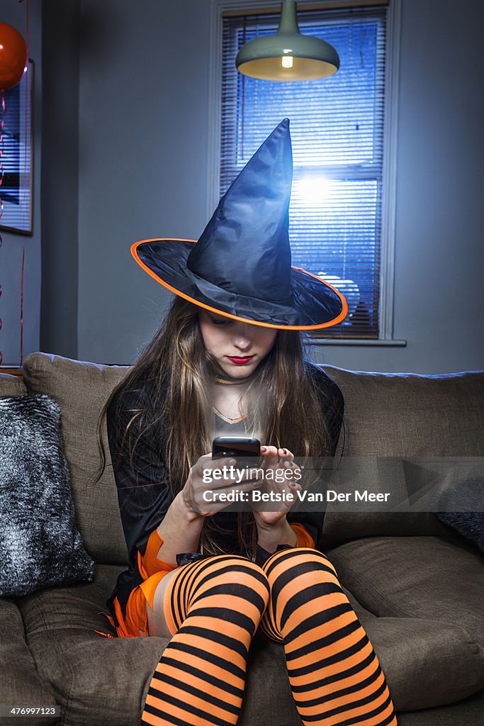 Halloween witch checking her mobile phone.