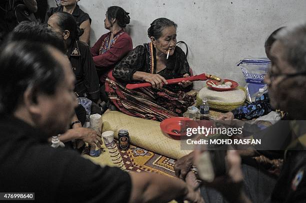 Jupirin Gombur a shaman from the Kadazan-Dusun tribe smokes as she holds a dagger called "hulu karis" after the Monolibabow rituals in Damat, in the...