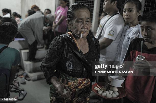 Jupirin Gombur a shaman from the Kadazan-Dusun tribe smokes as she offers prayers during the Monolibabow rituals in Damat, in the district of...