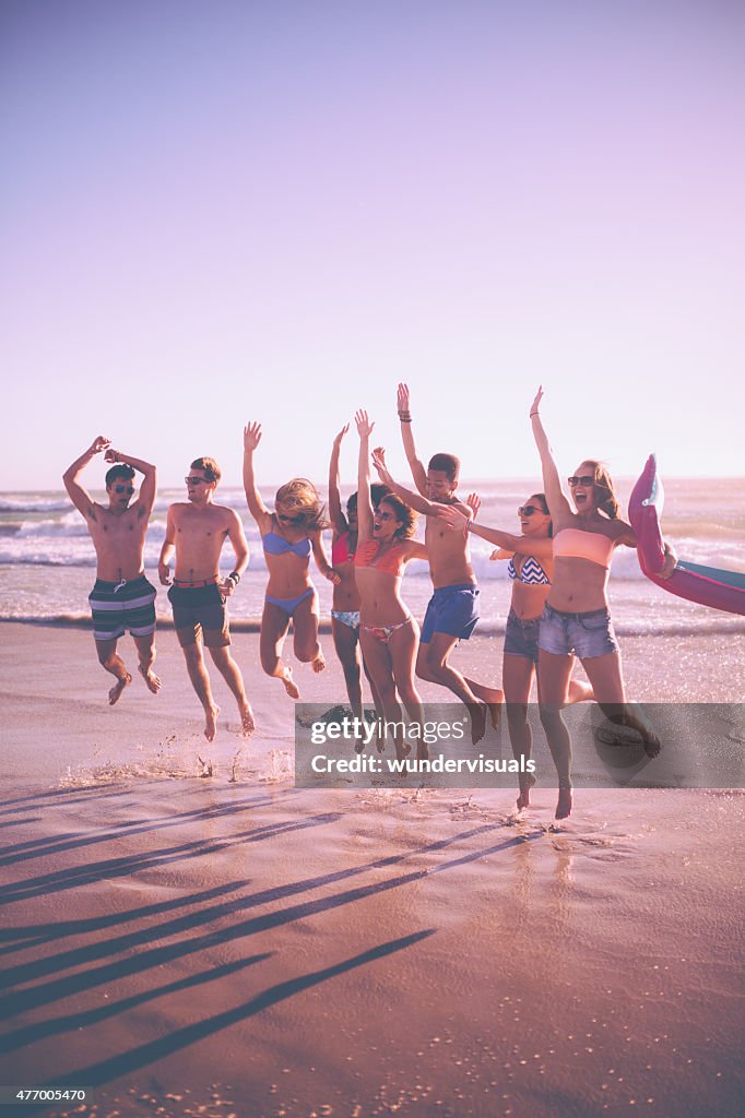 Young friends jumping at the water's edge at the beach