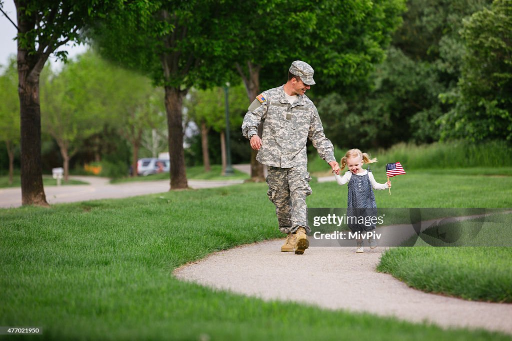 American soldier walking with his daughter