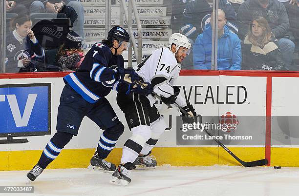 Dwight King of the Los Angeles Kings plays the puck along the boards as he battles Keaton Ellerby of the Winnipeg Jets during second period action at...
