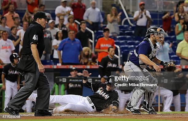 Christian Yelich of the Miami Marlins slides past Michael McKenry of the Colorado Rockies after scoring on a two RBI double by Giancarlo Stanton...