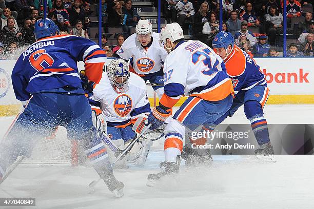 Jesse Joensuu and Matt Hendricks of the Edmonton Oilers attack the net against Brian Strait and goalie Evgeni Nabokov of the New York Islanders on...