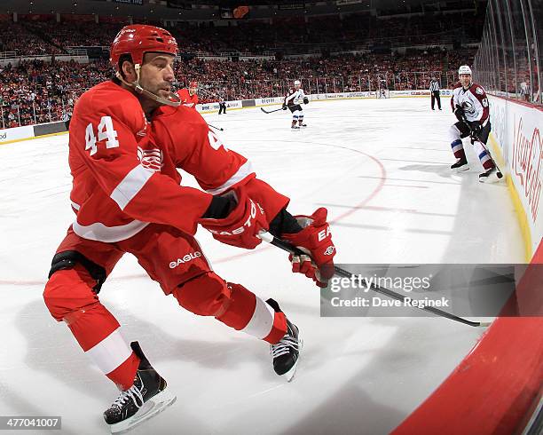 Todd Bertuzzi of the Detroit Red Wings reaches behind his body for the puck against defenseman Andre Benoit of the Colorado Avalanche during an NHL...