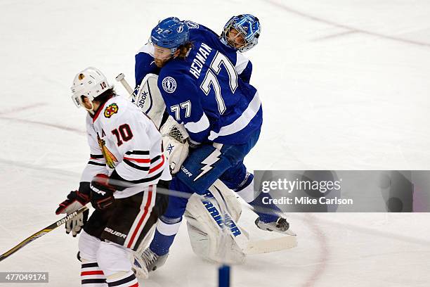 Ben Bishop of the Tampa Bay Lightning collides with Victor Hedman as Patrick Sharp of the Chicago Blackhawks skates past them with the puck on his...
