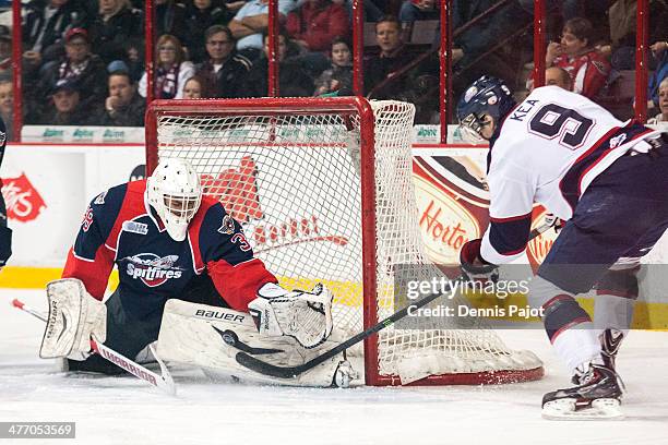 Alex Fotinos of the Windsor Spitfires defends against Justin Kea of the Saginaw Spirit on March 6, 2014 at the WFCU Centre in Windsor, Ontario,...