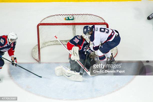 Justin Kea of the Saginaw Spirit battles in front of the net against Alex Fotinos of the Windsor Spitfires on March 6, 2014 at the WFCU Centre in...