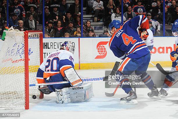 Taylor Hall of the Edmonton Oilers crashes the net as the puck crosses the goal line behind Evgeni Nabokov of the New York Islanders on March 6, 2014...