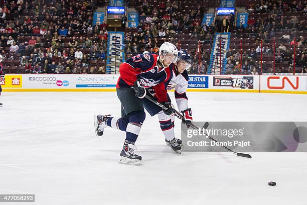 Luke Cairns of the Saginaw Spirit battles for the puck against Eric Diodati of the Windsor Spitfires on March 6, 2014 at the WFCU Centre in Windsor,...