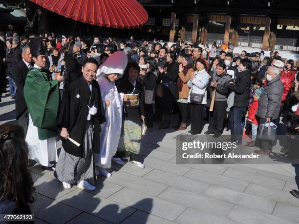 Bride and groom leads their wedding entourage past well wishers at a Shinto wedding at the Meiji-Jingu shrine in the Harajuku district of Tokyo. The...