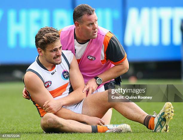 Stephen Coniglio of the Giants is helped from the ground by a trainer during the round 11 AFL match between the Collingwood Magpies and the Greater...