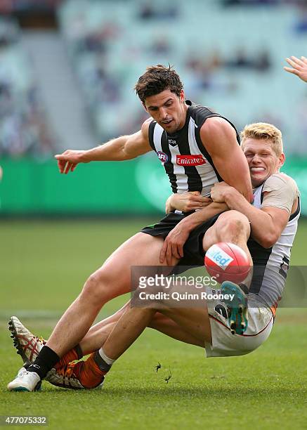 Scott Pendlebury of the Magpies kicks whilst being tackled by Adam Treloar of the Giants during the round 11 AFL match between the Collingwood...