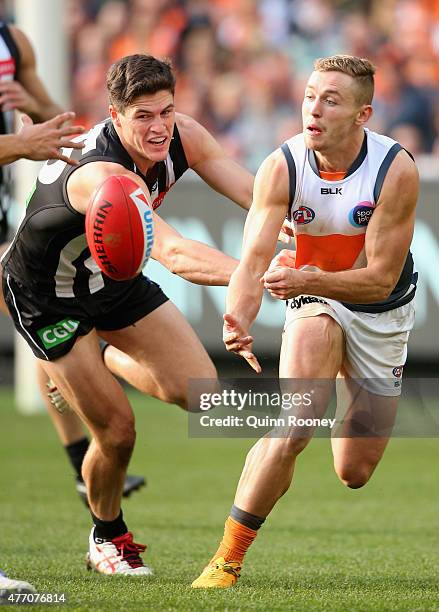 Devon Smith of the Giants handballs whilst being tackled by Jack Crisp of the Magpies during the round 11 AFL match between the Collingwood Magpies...