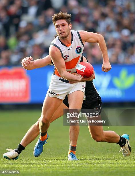 Tomas Bugg of the Giants handballs whilst being tackled during the round 11 AFL match between the Collingwood Magpies and the Greater Western Sydney...
